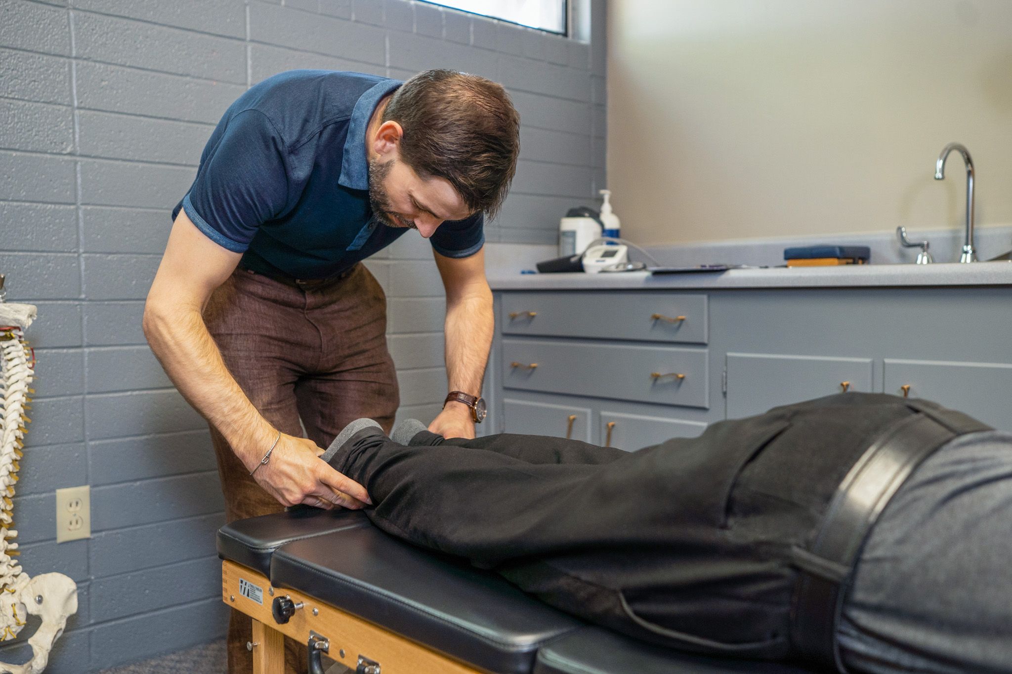 Dr. Clint Mausser adjusting a patient's leg on a treatment table